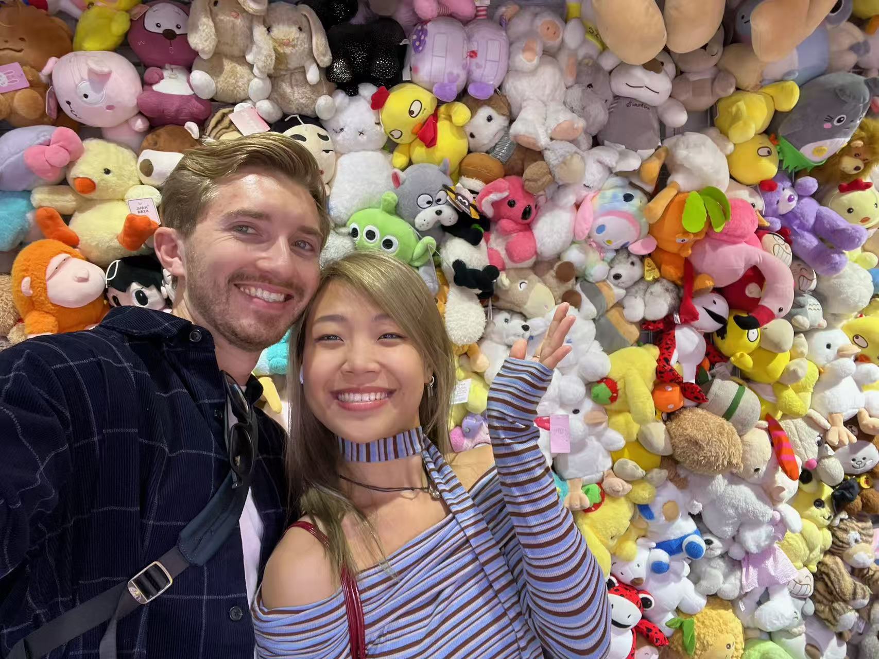 Michael and Lina in front of a wall of plush toys