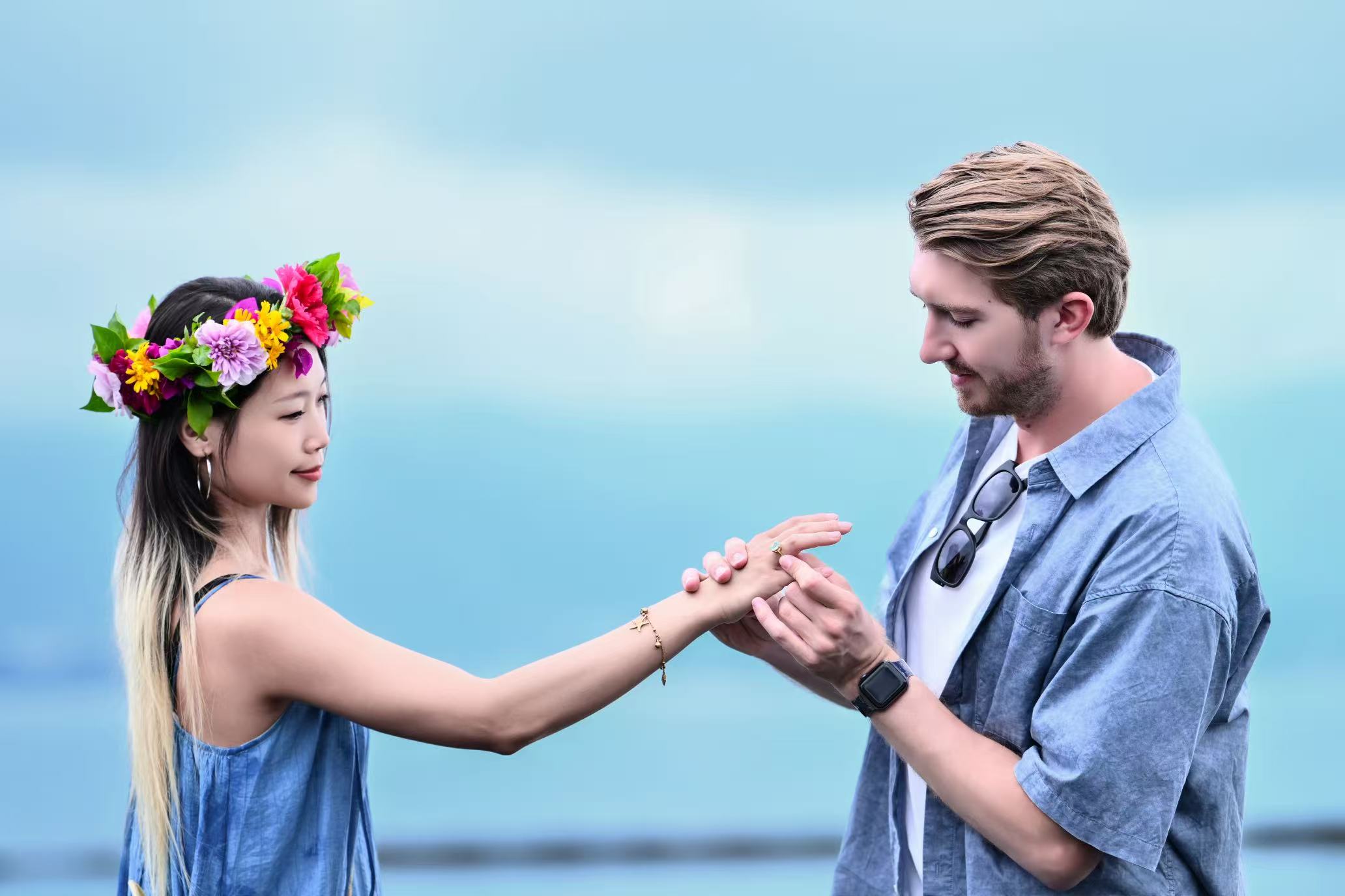 Michael slipping a ring onto Lina's finger by the water