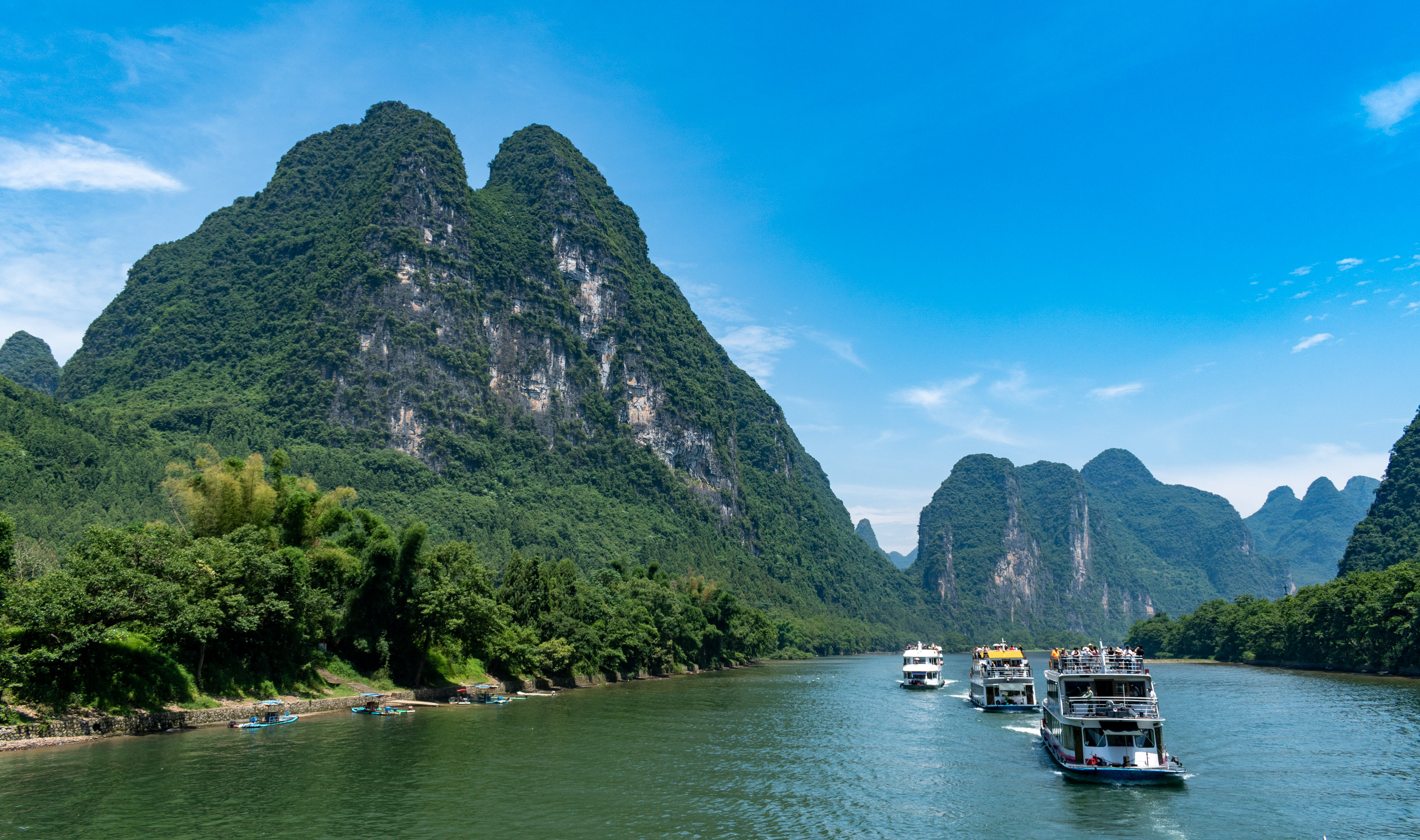 Cruise boats on the Li River beneath towering green karst peaks near Yangshuo